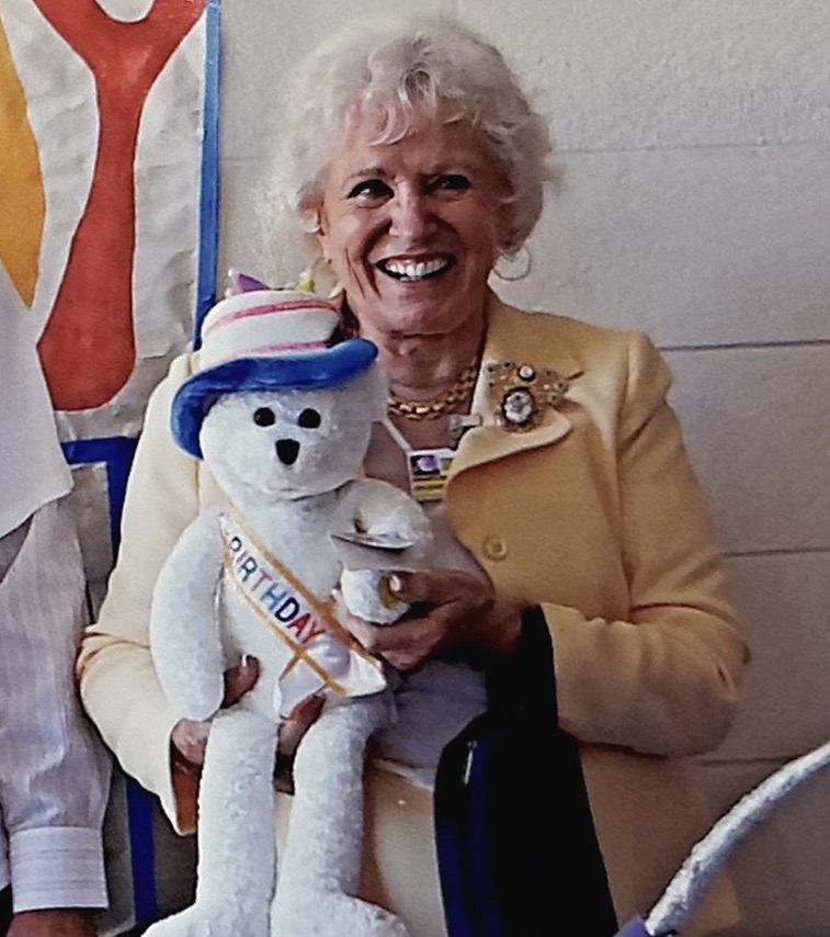 Smiling woman holding teddy bear.